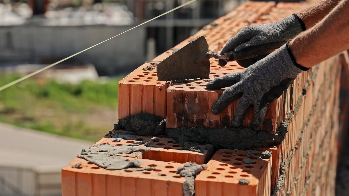Close-up of a mason laying bricks with mortar